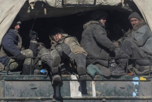 Ukrainian servicemen ride on a military vehicle as they leave area around Debaltseve
