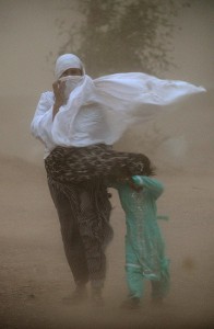 A Pakistani woman and child struggle to walk in a dust storm